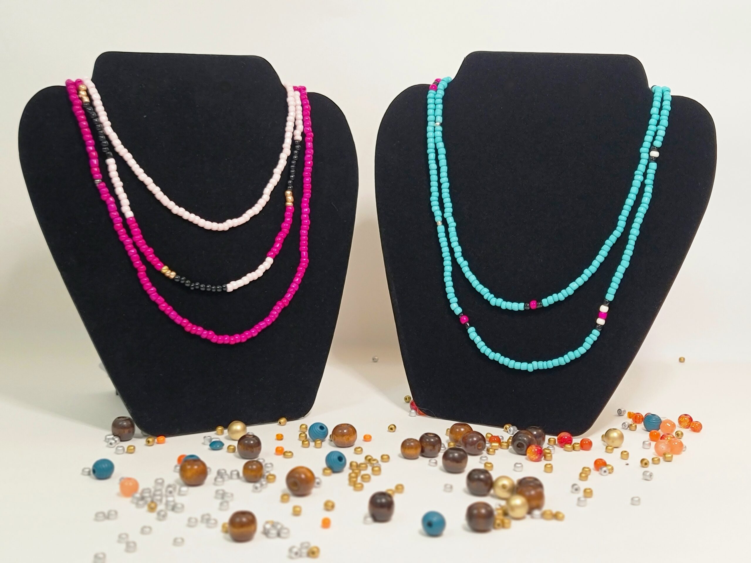 Two sets of beaded necklaces displayed. One in hot pink, barely pink, and black, and the other in turquoise with accents of magenta, black, and ivory